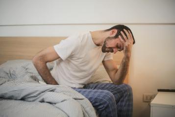 Male sitting in bed feeling unwell