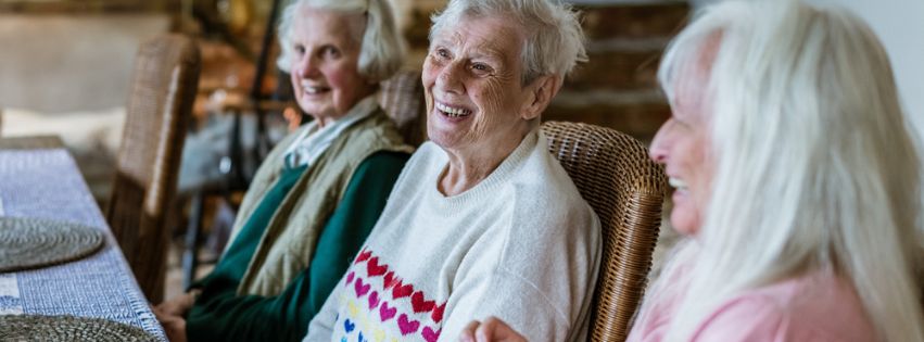 3 older ladies sitting at a table laughing