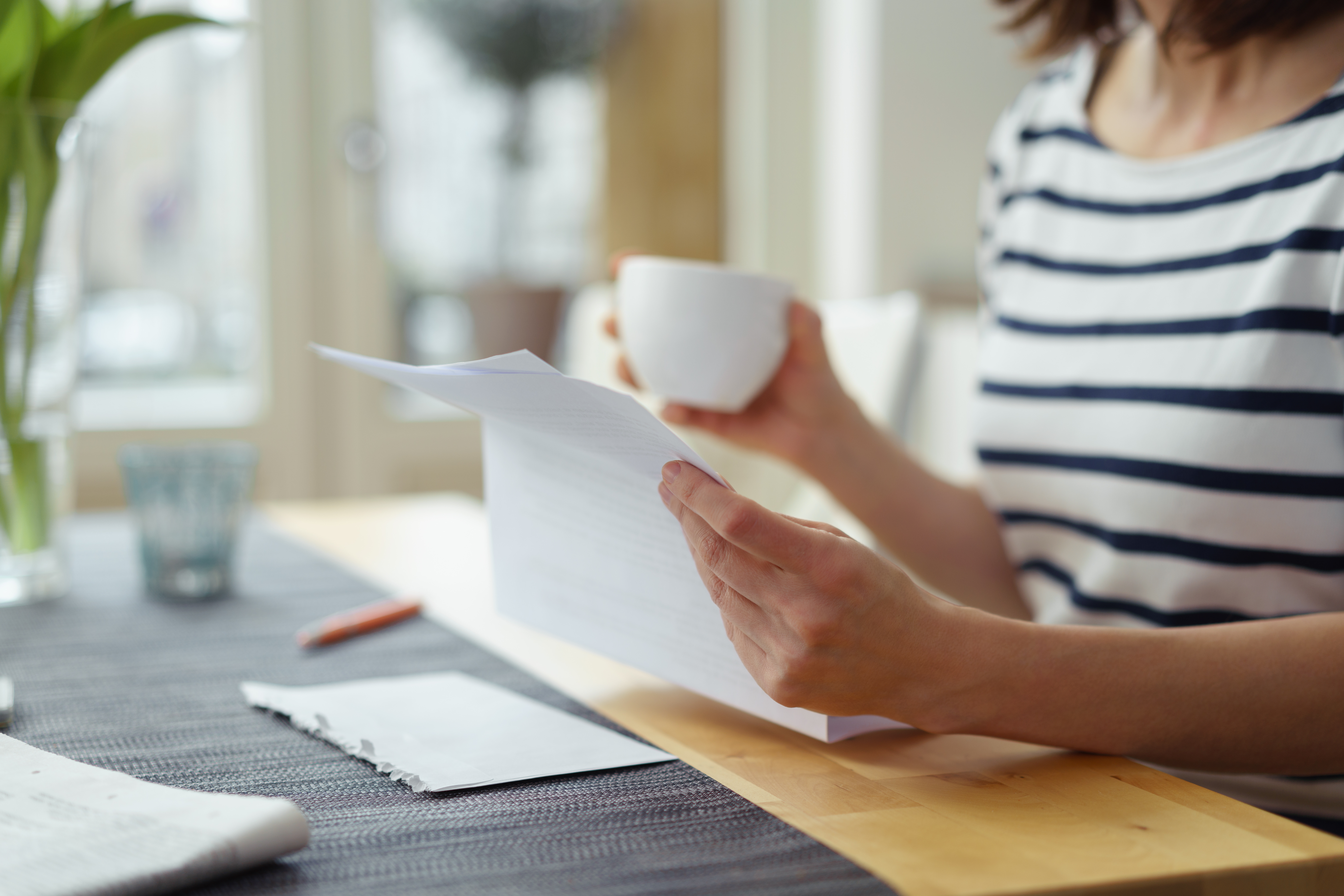 Lady holding a letter by laptop