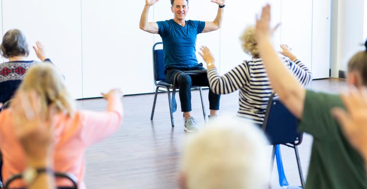 Group of older people doing chair exercises 