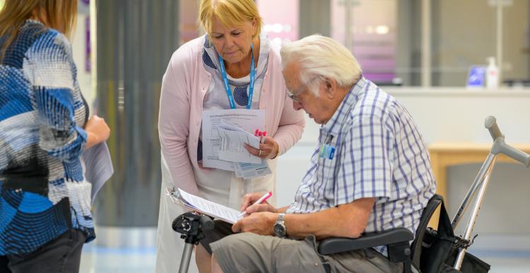 Healthwatch lady chatting to a gentleman in a mobility scooter 