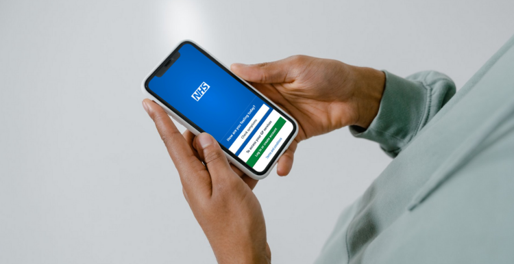 A mobile phone in hands looking at the NHS app