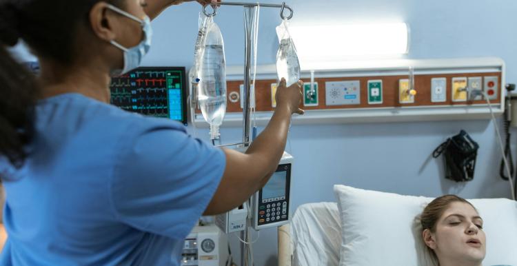 A female nurse adjusting the female hospital patient's drip