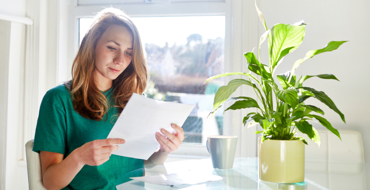 Lady sitting in her kitchen reading a letter