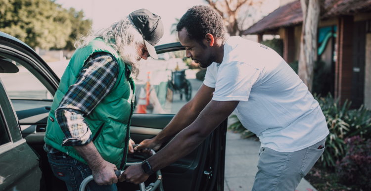A younger man helping an elderly person out of the car