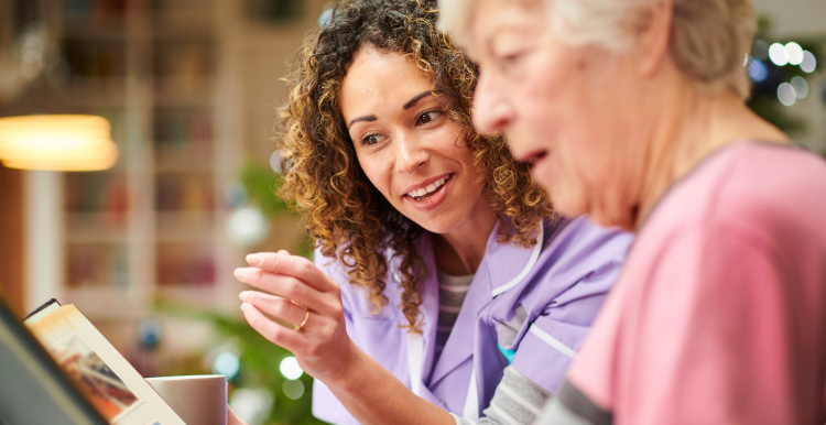 A nurse and a lady looking through old photo albums