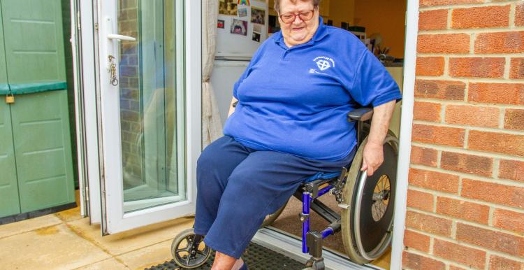 Lady in her wheelchair leaving the house
