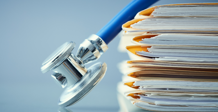 Patient records in a file with a stethoscope laying next to files