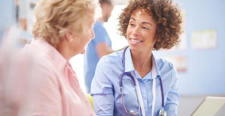 Elderly patient sitting and talking to her doctor