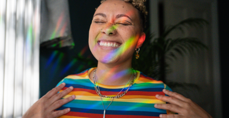 Young lady with a multicoloured top smiling and shining in light 