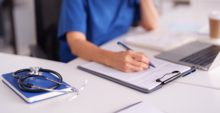 A medical staff member filling out of a form while sitting at her desk