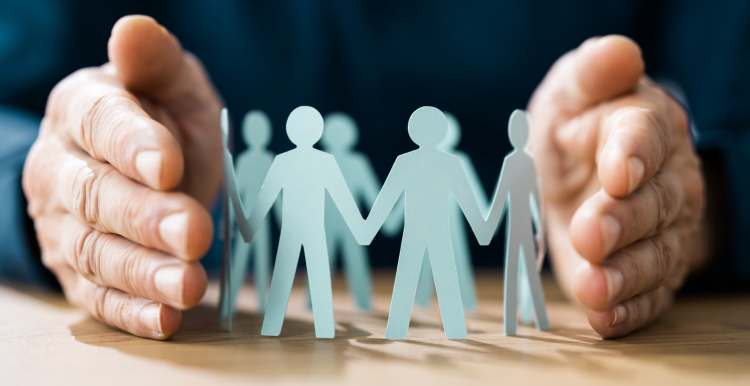 Adult hands surrounding paper cutouts of adult body shapes