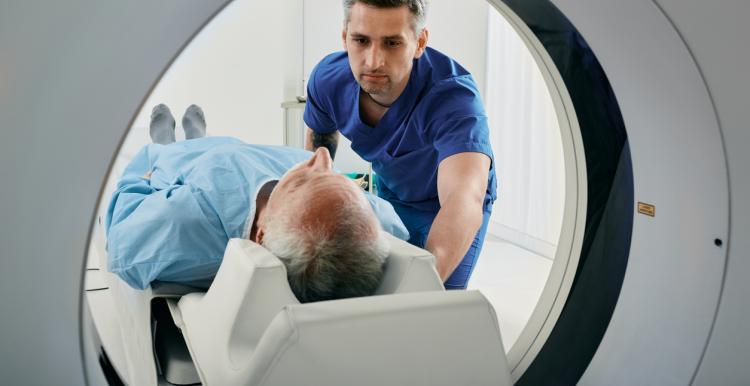 Senior man going into CT scanner. CT scan technologist overlooking patient in Computed Tomography scanner during preparation for procedure