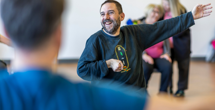 Male chair exercising with a group of other people while smiling
