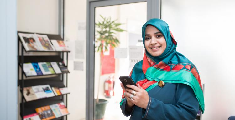 Girl smiling at the camera holding a phone