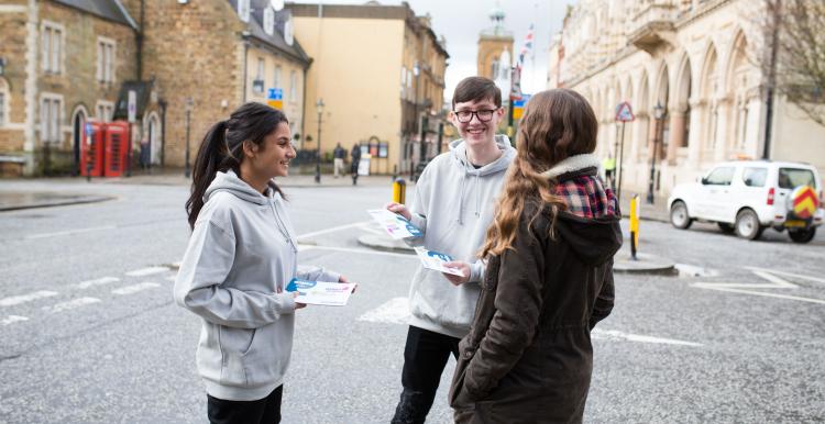 Young Healthwatch volunteers standing outside, smiling