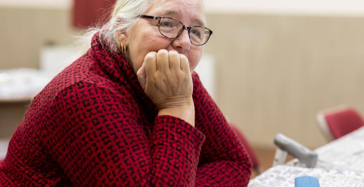 Older lady sitting at a table thinking and looking sad