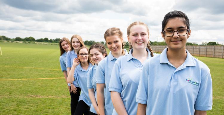 A group of youth volunteers standing in a line outside on a field