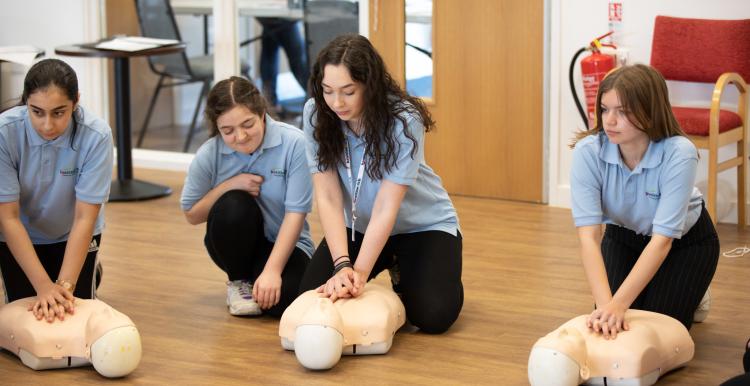 Group of teenagers learning CPR in a classroom