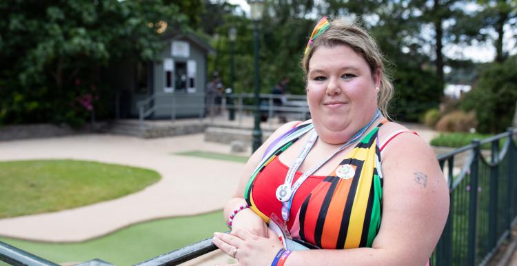 Woman standing against fence, smiling