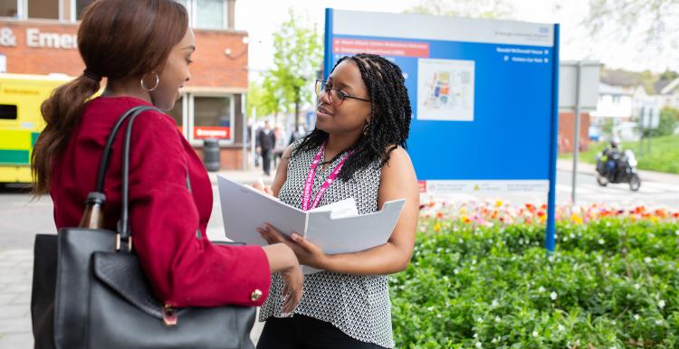 Two people looking at a folder outside a hospital