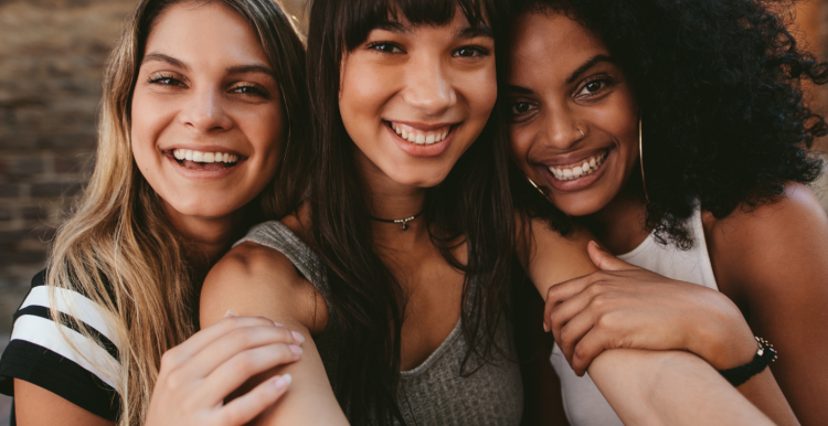 Three women sitting next to each other and smiling 