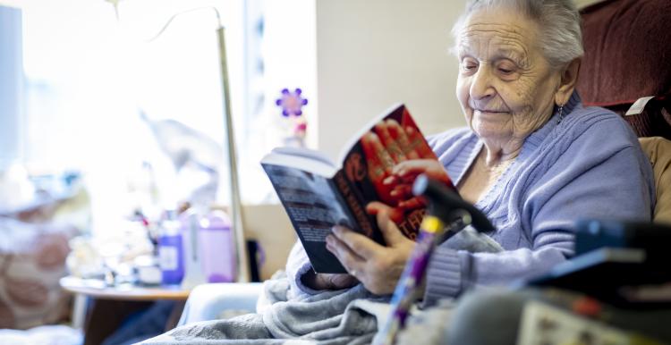 Older lady sitting in her chair reading a book