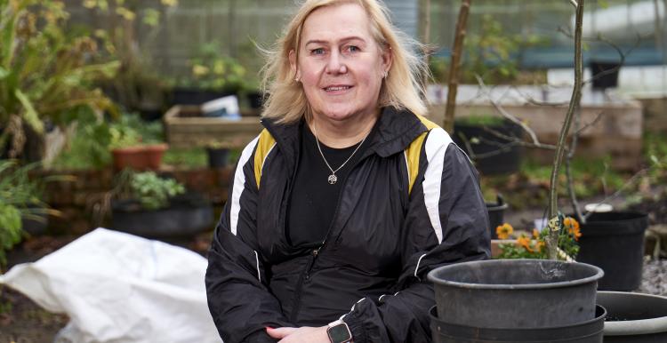 Lady doing some gardening, smiling at the camera. Image from Centre for Ageing Better
