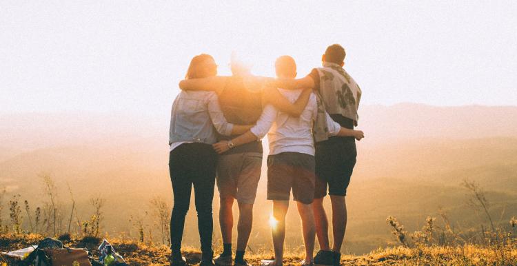Family hugging facing the sun set overlooking a mountain view 