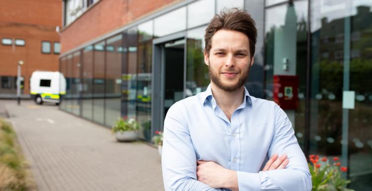 A man crossing his arms, standing face on outside a hospital