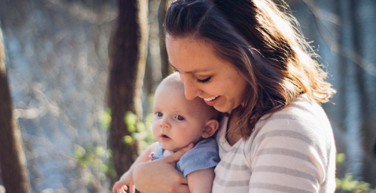 Mum carrying baby near trees