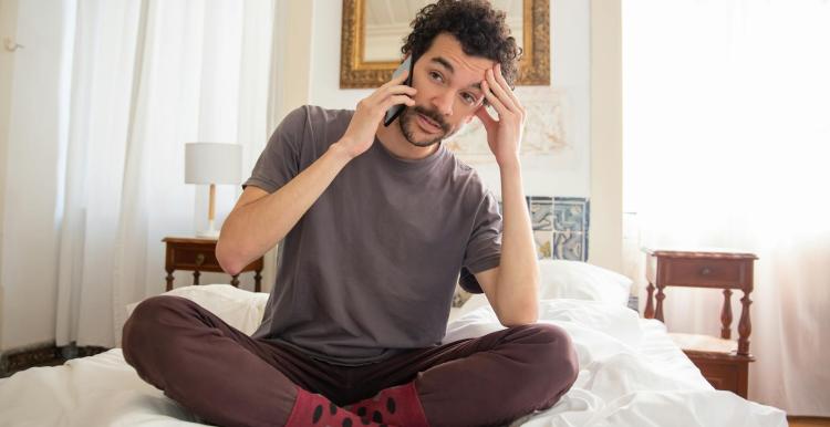Man sitting on his bed talking on the phone