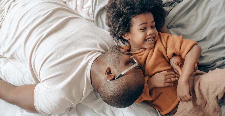 Dad and son playing and smiling while laying down