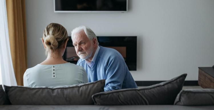 Older male sitting on a sofa chatting to a lady