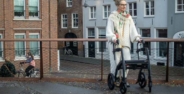 Older lady walking in a street using a walking aid