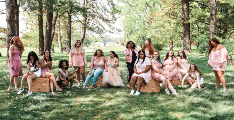 A group of women, different ages in a forest sitting on hay bales