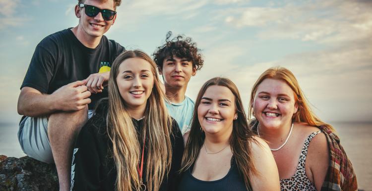 Group of young teenagers at the beach smiling at the camera