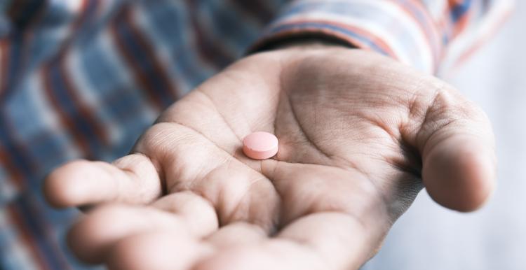 Man holding a pill out to the camera