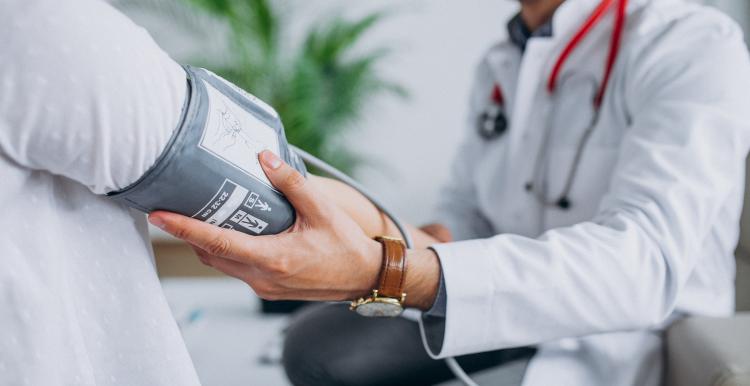 Young male doctor with patient measuring blood pressure
