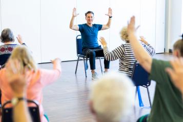 Group of older people doing chair exercises 