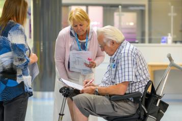 Healthwatch lady chatting to a gentleman in a mobility scooter 