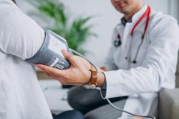 Young male doctor with patient measuring blood pressure
