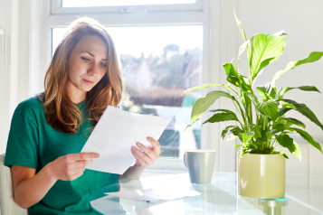 Lady sitting in her kitchen reading a letter