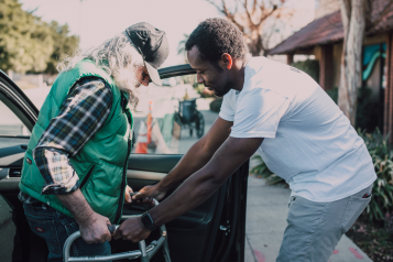 A younger man helping an elderly person out of the car