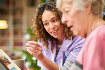 A nurse and a lady looking through old photo albums