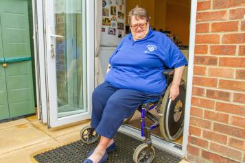 Lady in her wheelchair leaving the house