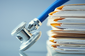 Patient records in a file with a stethoscope laying next to files