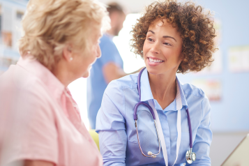 Elderly patient sitting and talking to her doctor