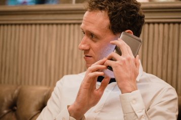 A close-up of a man who has his smartphone in his hand and he is using a visually impaired mobile app to help assist him.