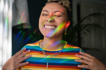 Young lady with a multicoloured top smiling and shining in light 
